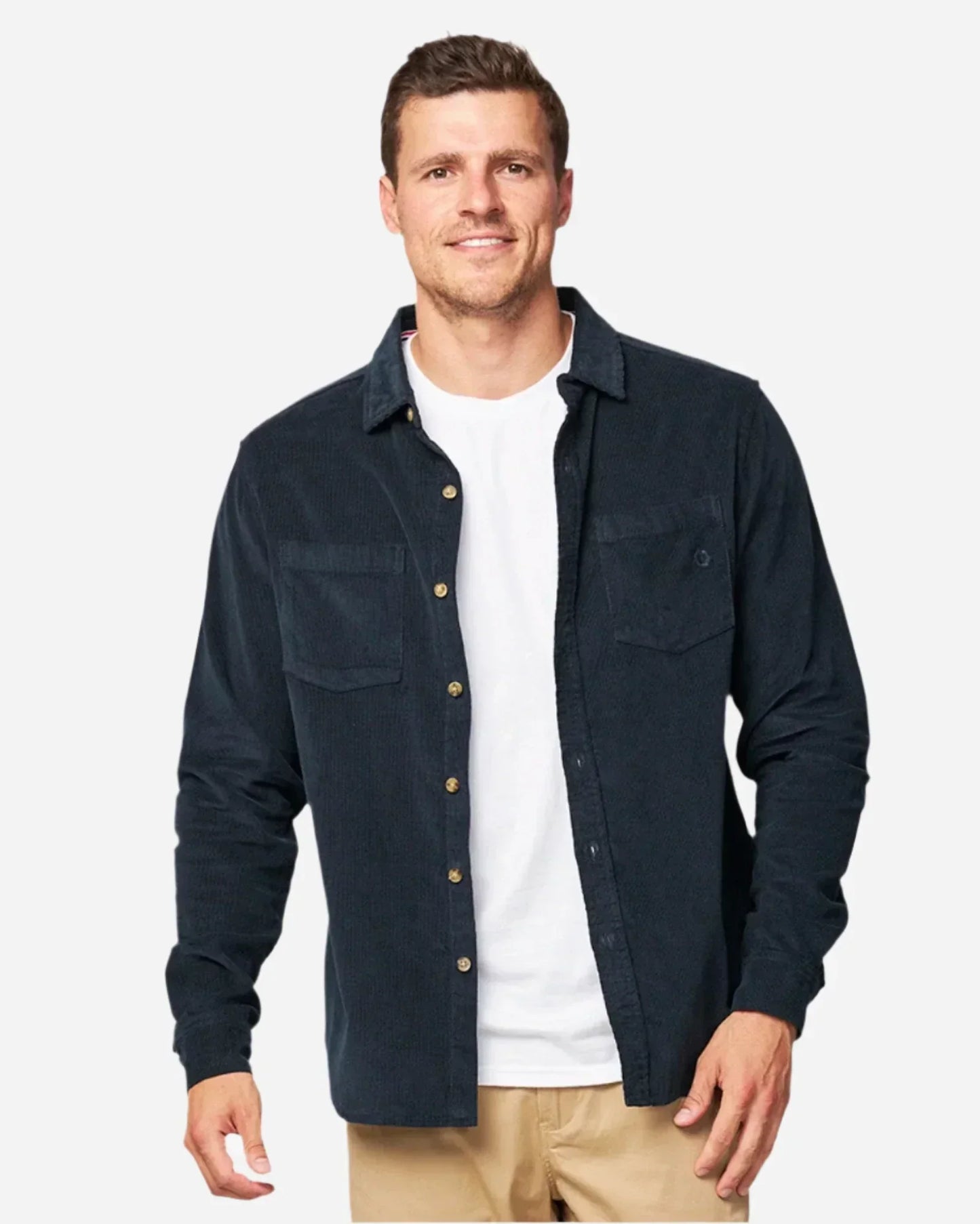 A male model posing wearing the unbottened Okanui Corduroy Ledge Long Sleeve Shirt in Navy colour worn over a white t-shirt.