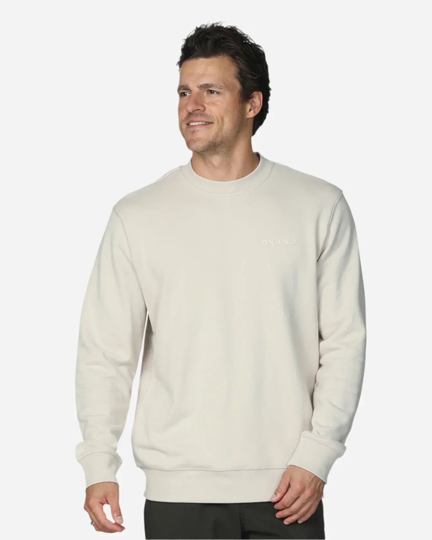 A man dressed in dark pants, white shoes, and a plain sweatshirt top facing the left side.