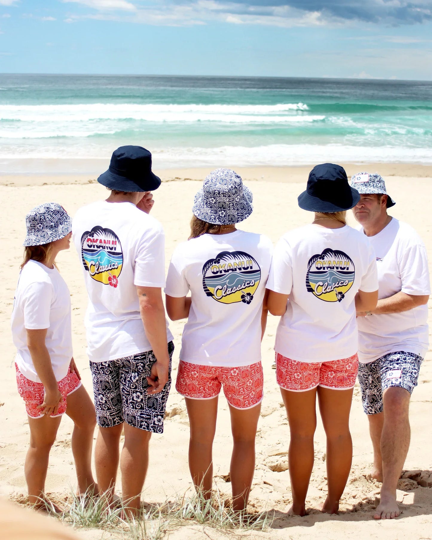 Group of people wearing Okanui white tshirt and Okanui Gotcha4Life quick dry swim shorts in Red
