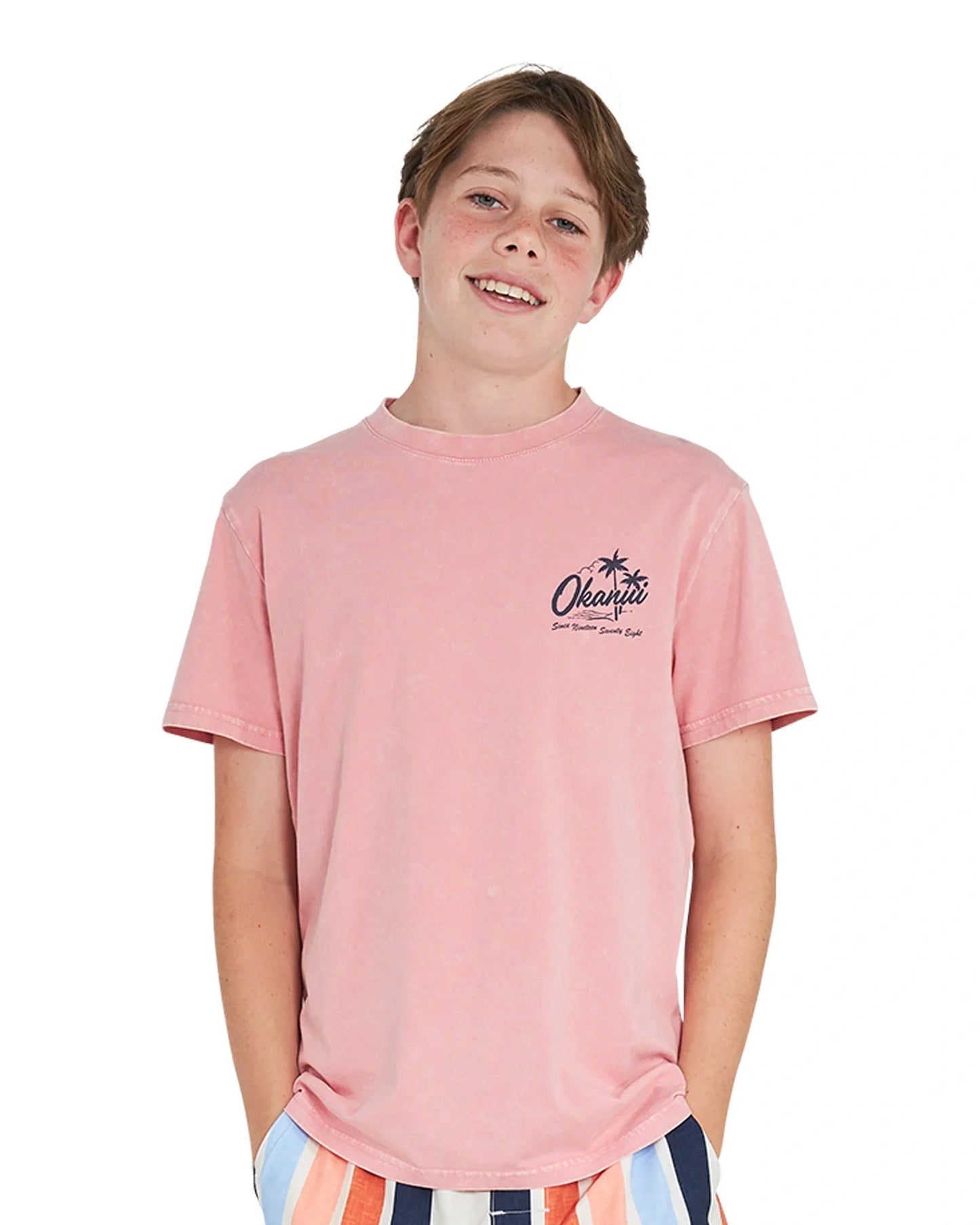 Hands in pocket pose of a boy wearing the Okanui Postcard Tee T-shirt in Washed Pink