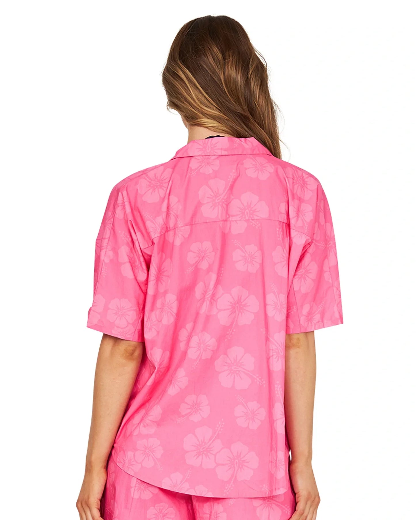 The woman is dressed in hibiscus pink top and short showing the back details.