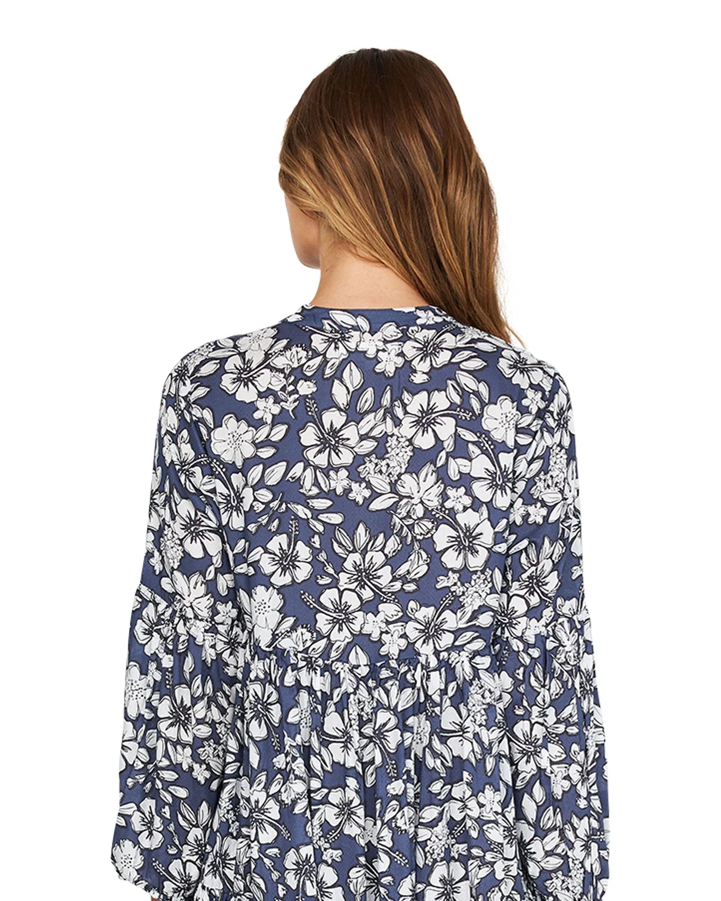 A woman is wearing a flower garden design dress in a midi length showing the back details.