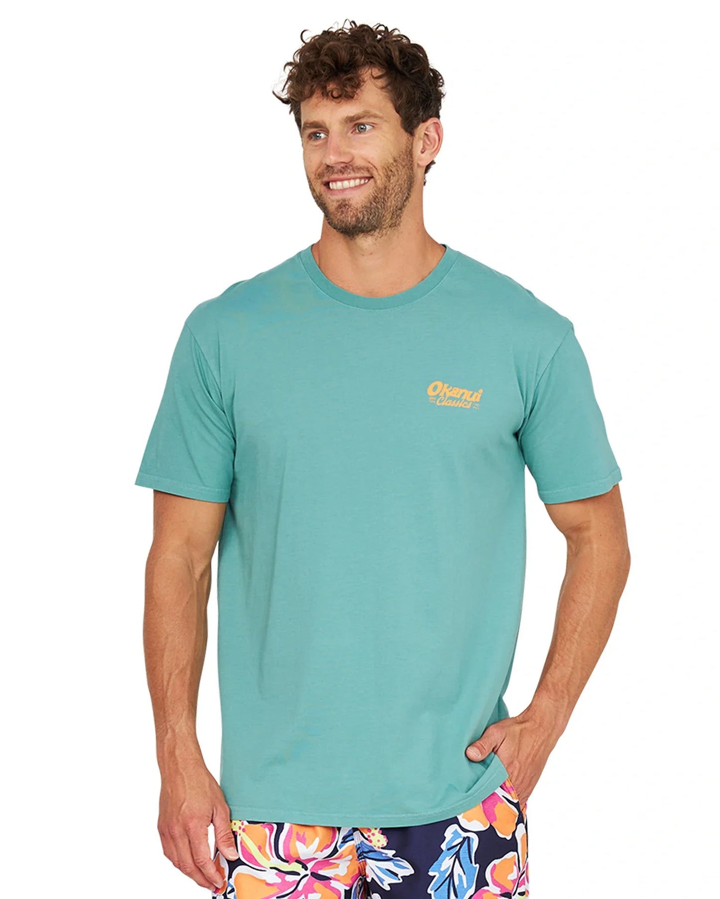A front view of a model wearing the Okanui Big Screen T-Shirt in washed teal color with his hand in his pocket.