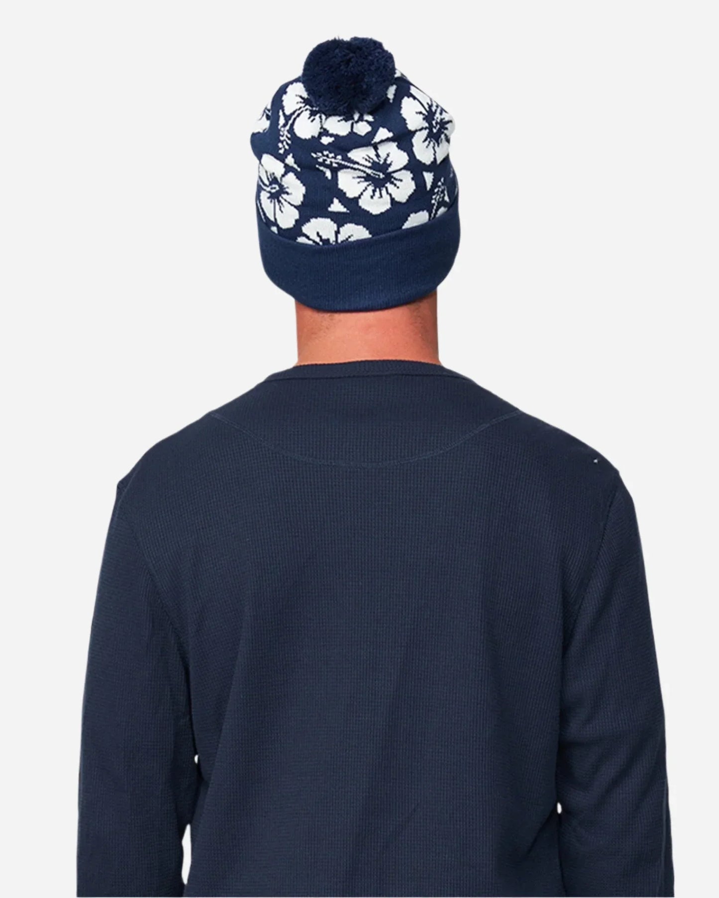Back view of a male model wearing the Okanui Hibiscus Rib knit Pom Pom beanie hat in Navy color