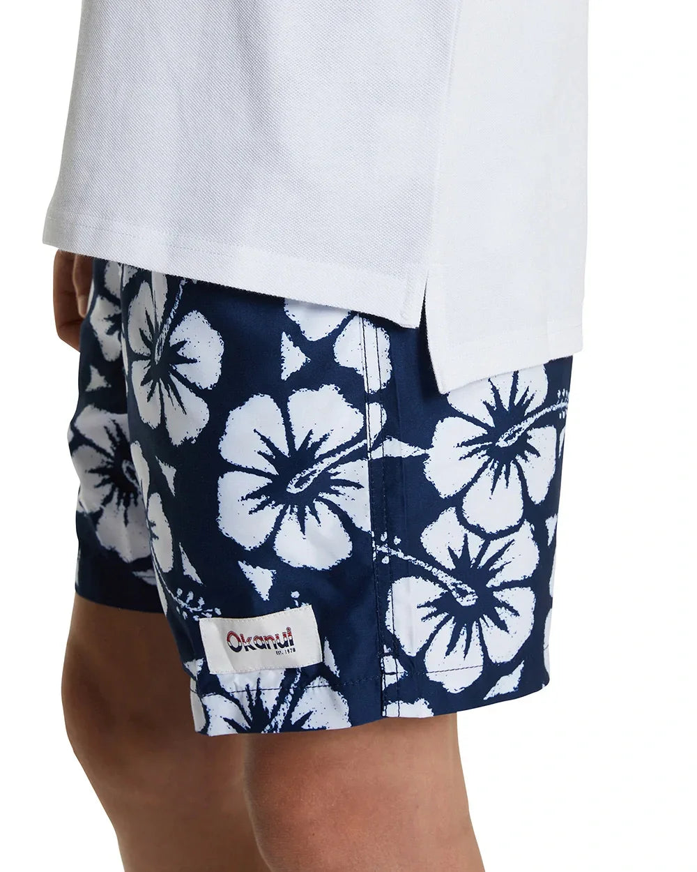 Photo of a young male model wearing the Okanui Classic White Polo Shirt with a stepped hemline cut for style
