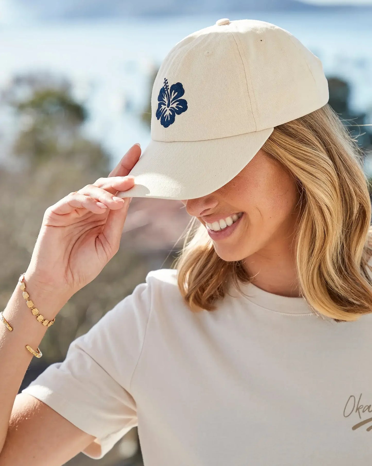 Left side view of a female model wearing the Okanui Ikon trucker cap in Winter White