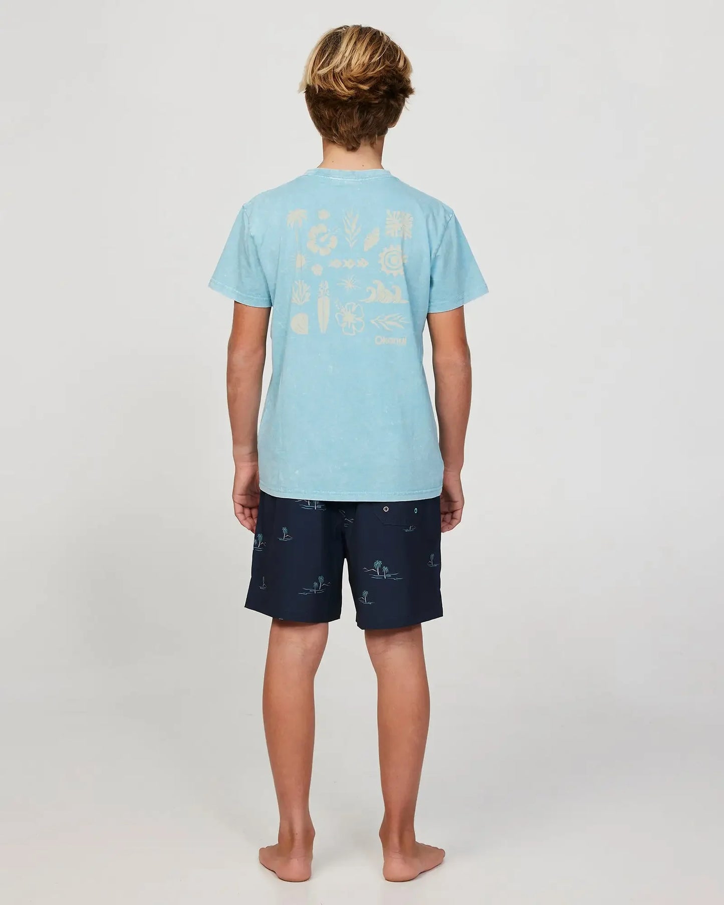 Full body back view of a boy model wearing the Okanui Curiosity T-shirt for boys in Seafoam