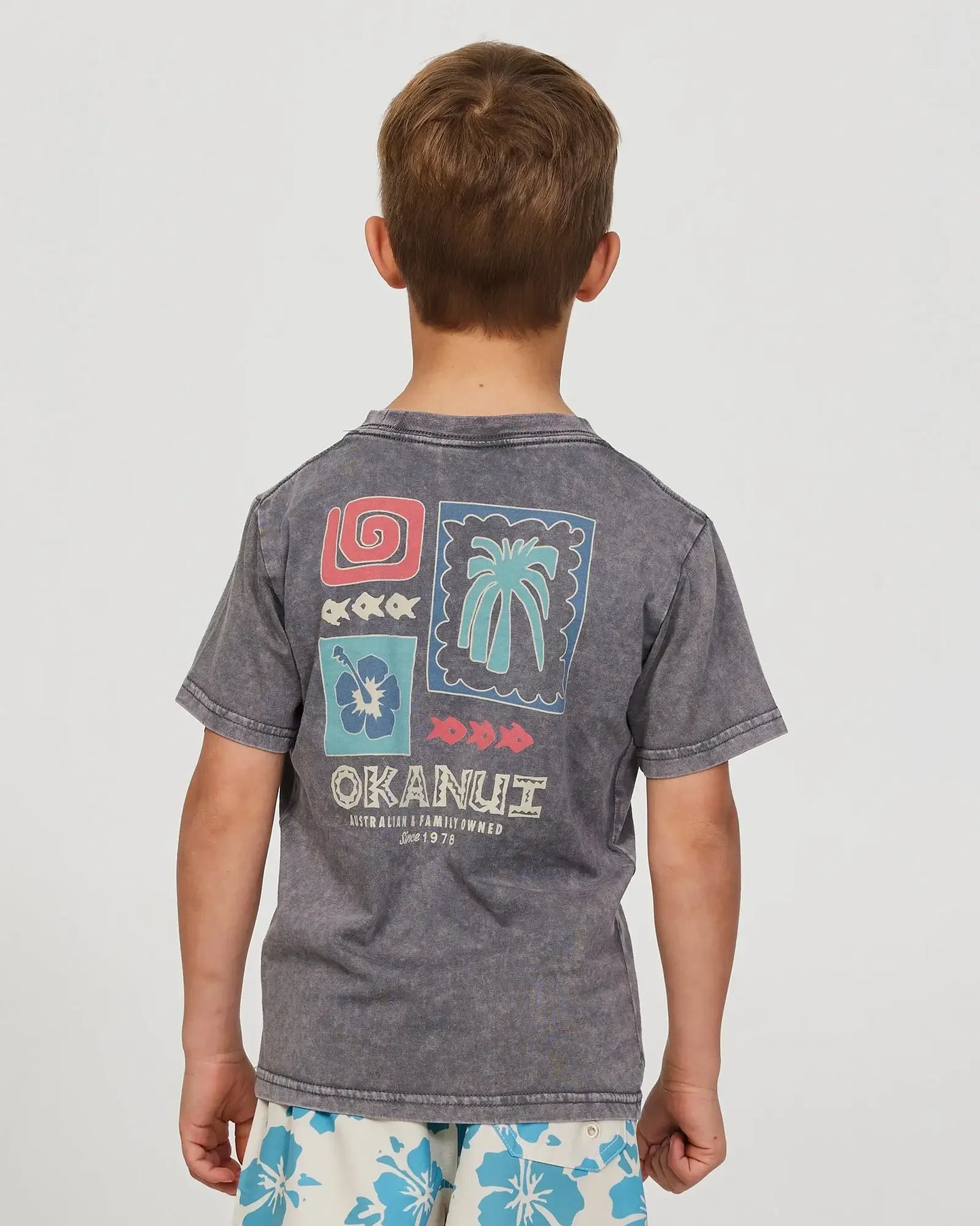 Closeup back view of a little boy wearing the Okanui Cut Paste T-shirt for boys in Washed Black
