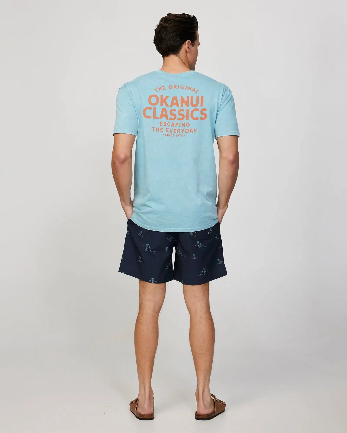 Full body back view of a male model wearing the Okanui Mens Decal Tee T-shirt in Seafoam