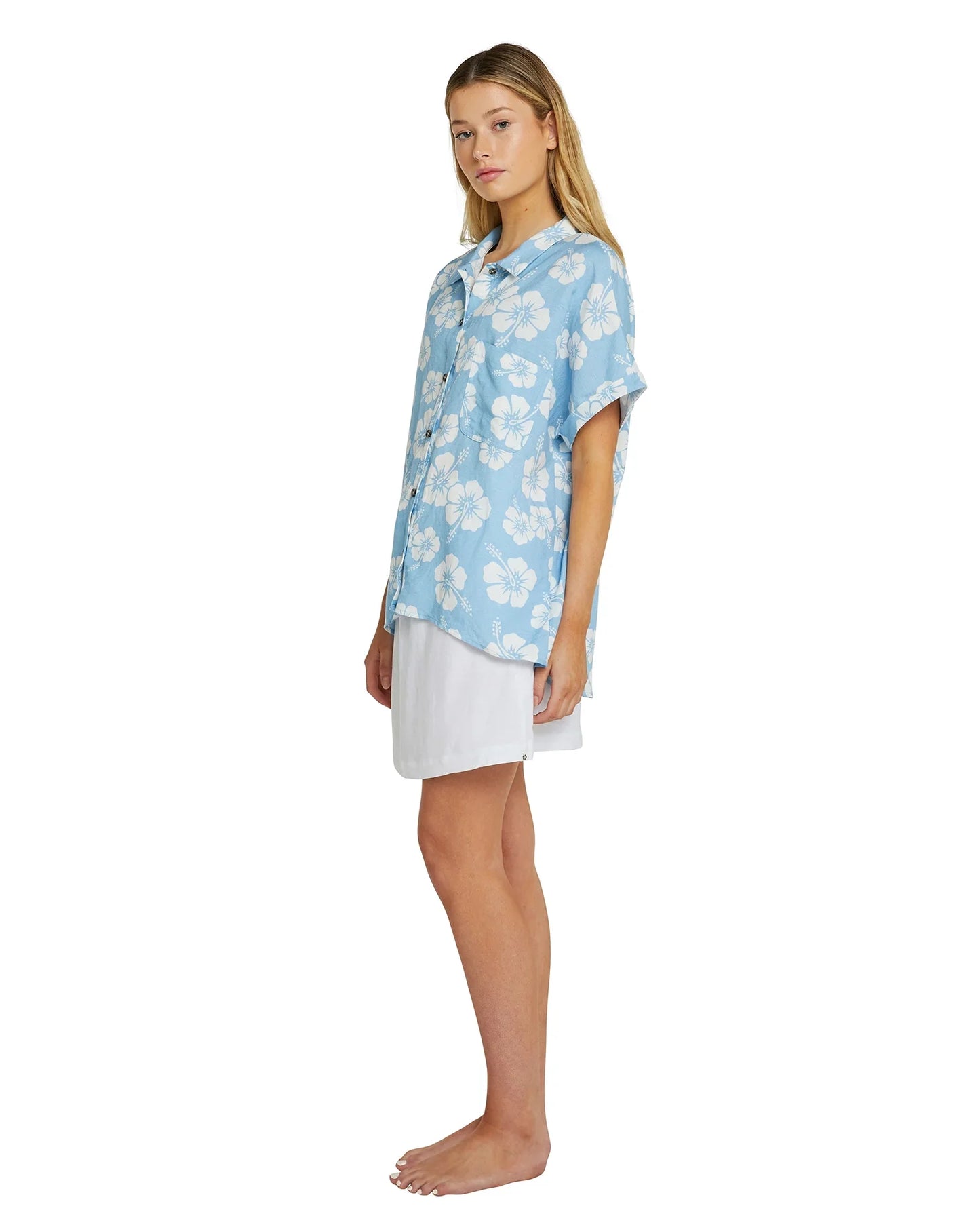 Left angled front view of a female model wearing the Okanui womens button up shirt in sky blue