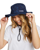 A half body view of a female model wearing a white t-shirt and the Okanui Bucket Boonie Hat featuring a neck cord and its wide brim.