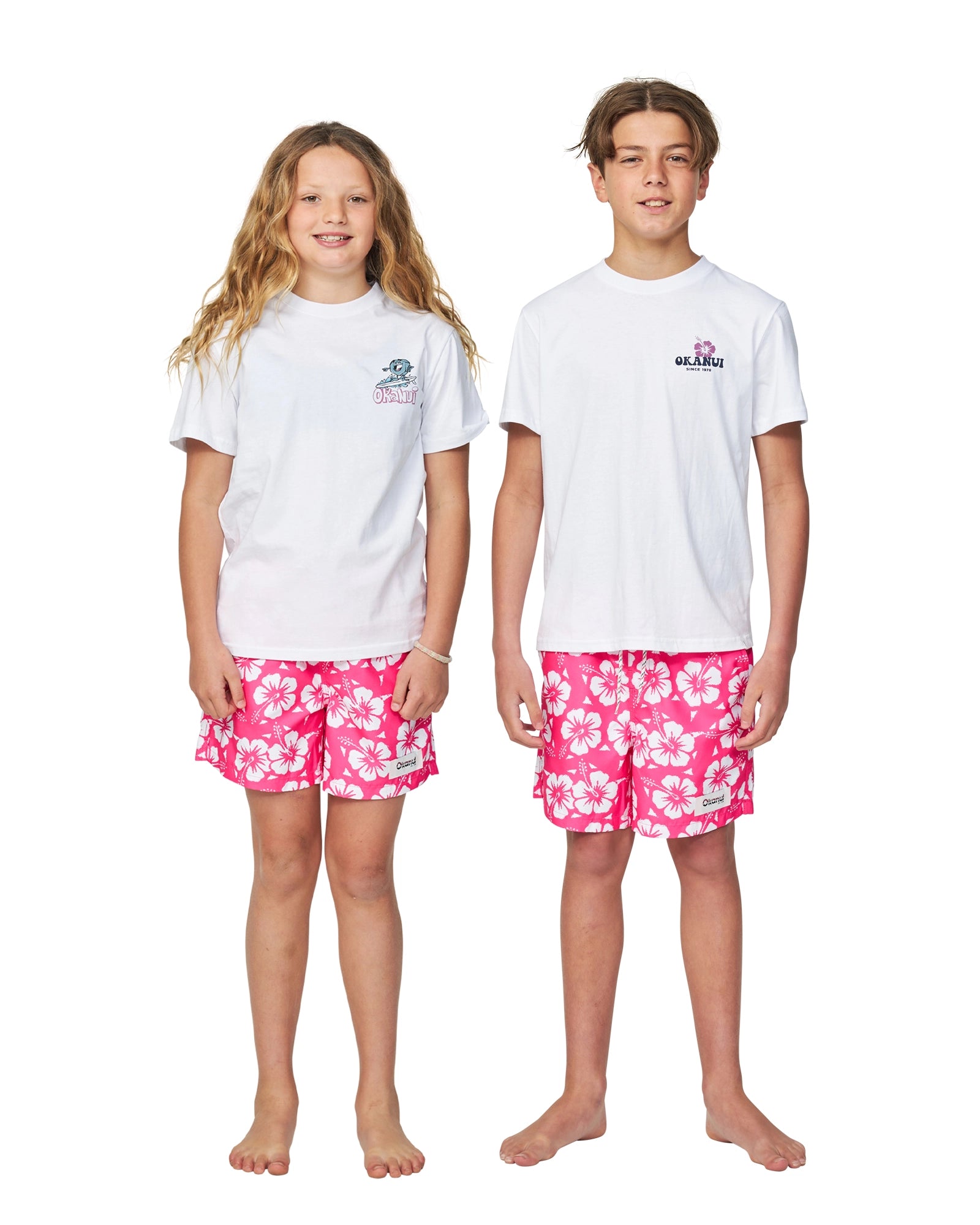 A girl and a boy in white T-shirt wearing the Okanui boys swim shorts in Hibiscus Hot Pink