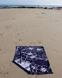 Spreaded Okanui Classic Hibiscus Beach Towel in navy with beach background