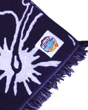Close up view of the Okanui badge of the Outer side of the Okanui Classic Hibiscus Navy Beach Towel