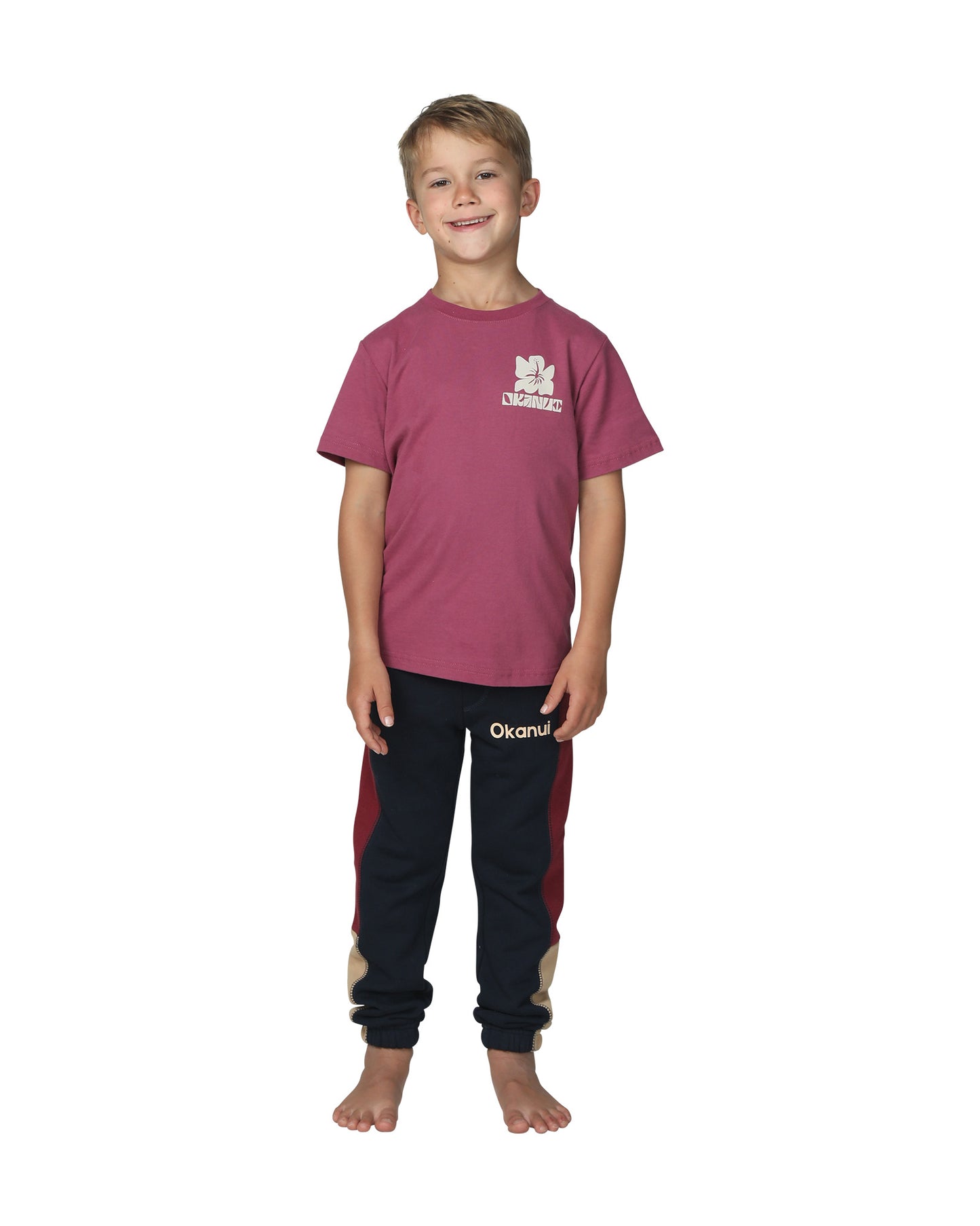 Full body front view of a little boy wearing the Okanui Boys Track pants trackies in Navy Multi