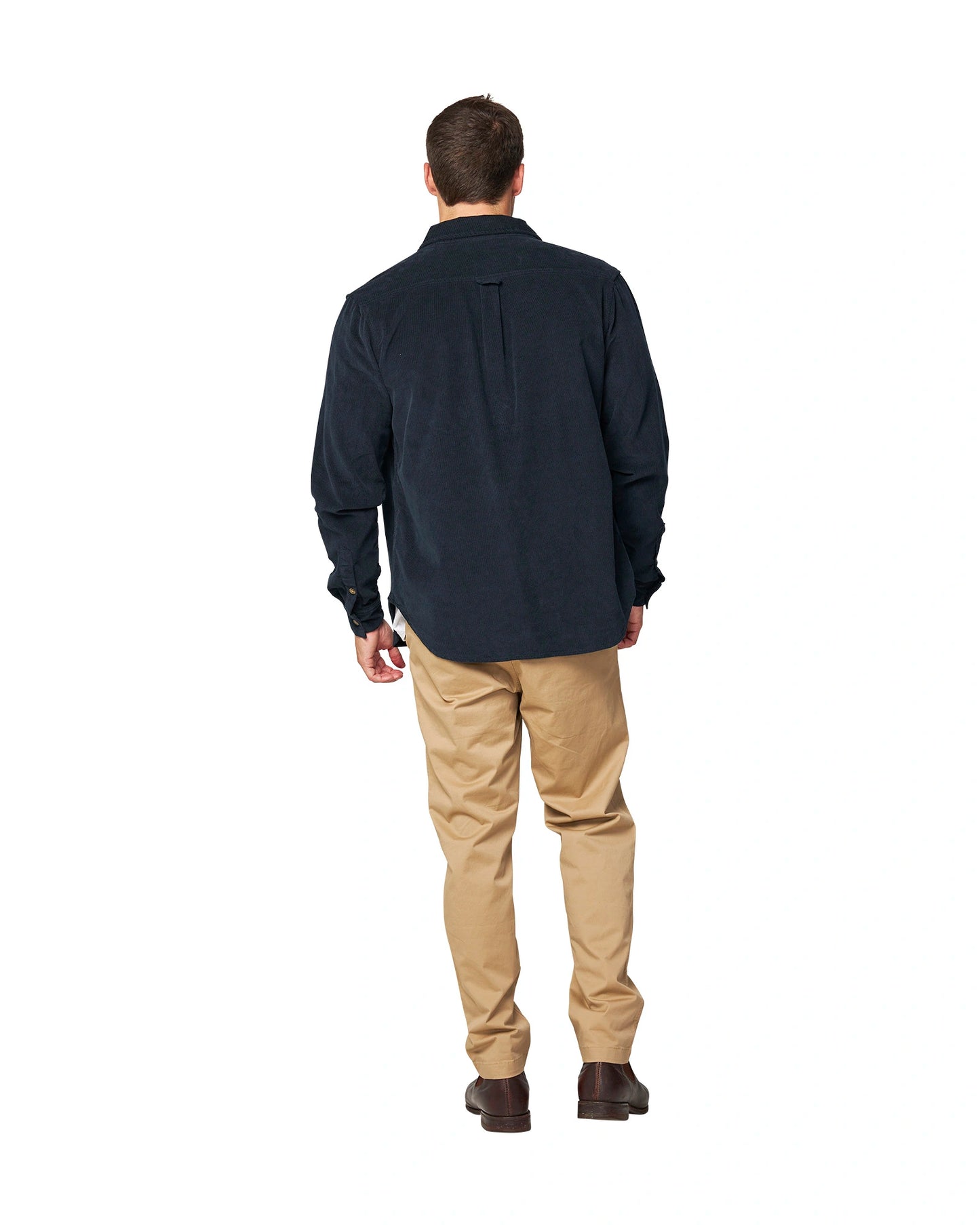 A full body back view of a male model posing wearing the unbottened Okanui Corduroy Ledge Long Sleeve Shirt in Navy colour worn over a white t-shirt.