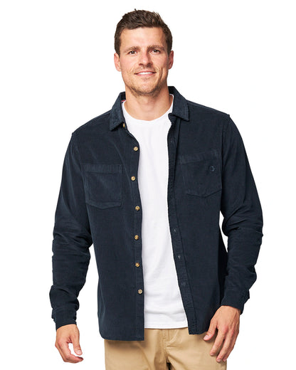 A male model posing wearing the unbottened Okanui Corduroy Ledge Long Sleeve Shirt in Navy colour worn over a white t-shirt.