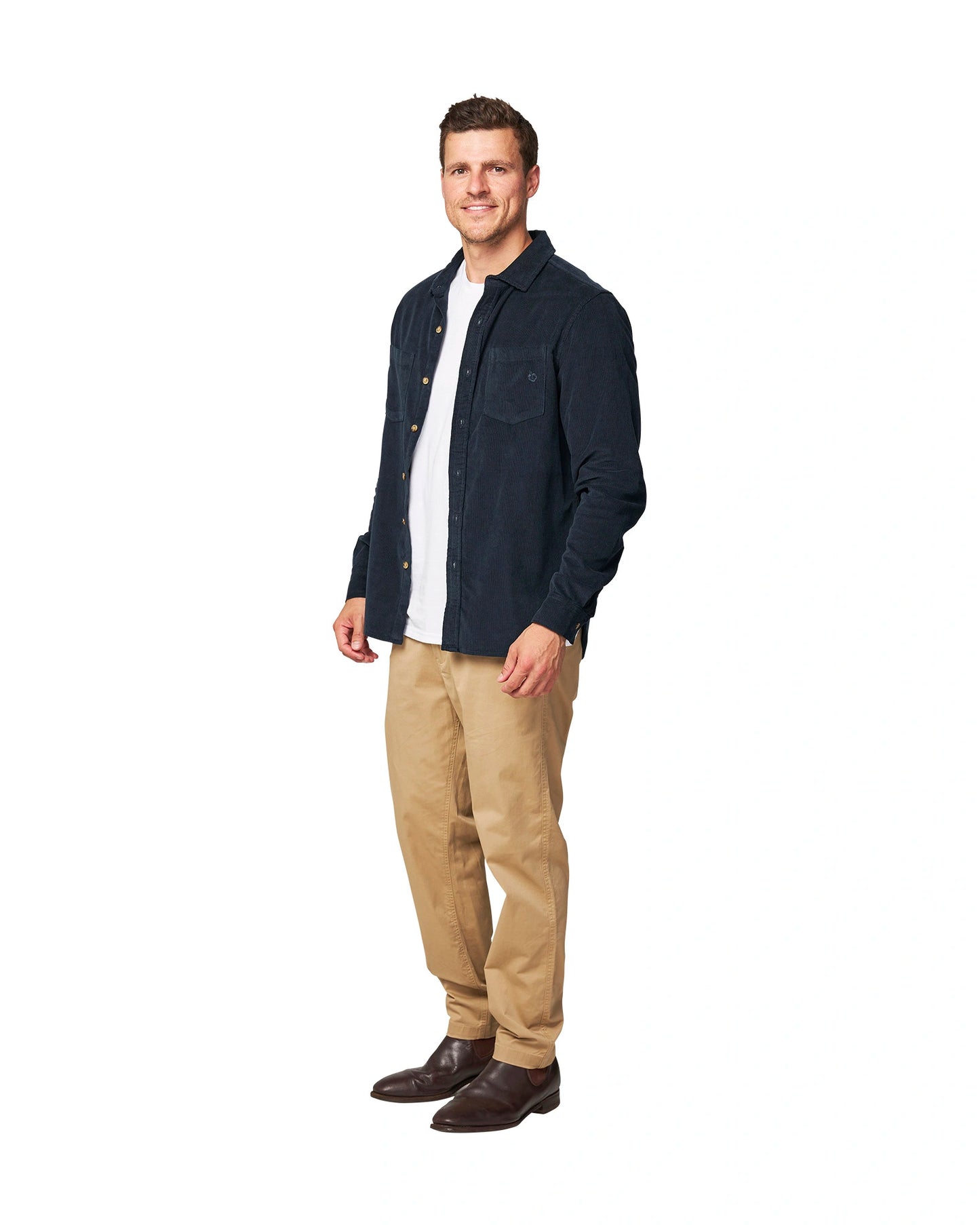 A full body view of a male model posing wearing the unbottened Okanui Corduroy Ledge Long Sleeve Shirt in Navy colour worn over a white t-shirt.