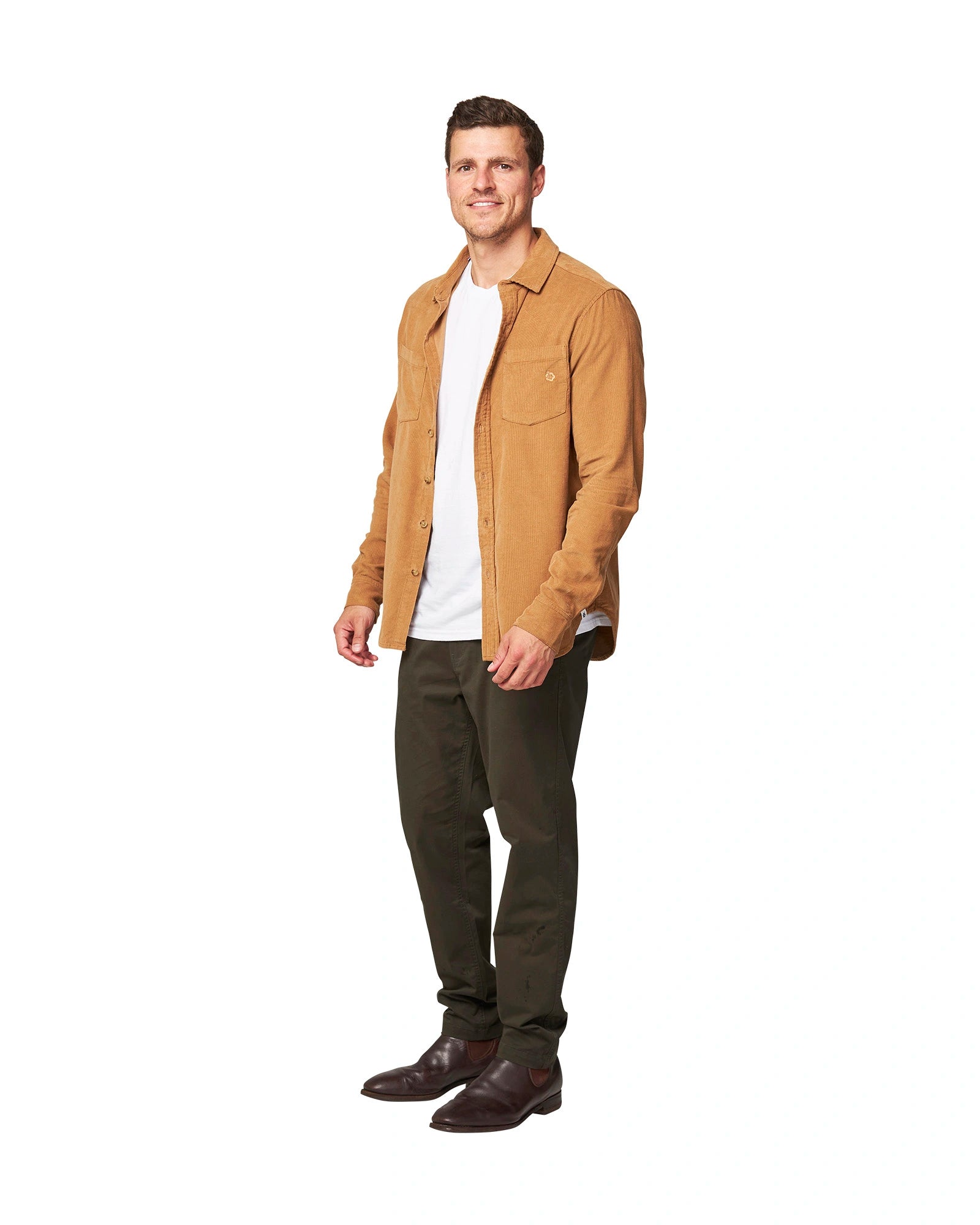 Full front view of a male model wearing the unbuttoned Okanui Corduroy Ledge Long Sleeve Shirt in Sand colour over a white t-shirt paired with olive colour pants and formal shoes..