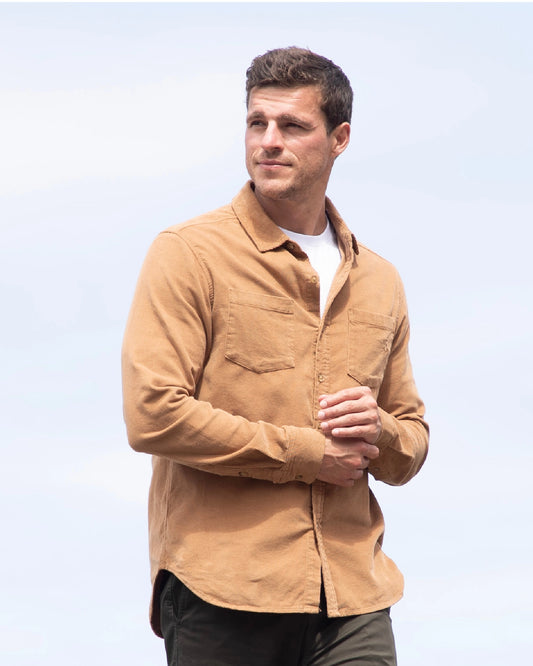 A man posing and looking at the distance wearing the Okanui Corduroy Ledge Long Sleeve Shirt in Sand colour.