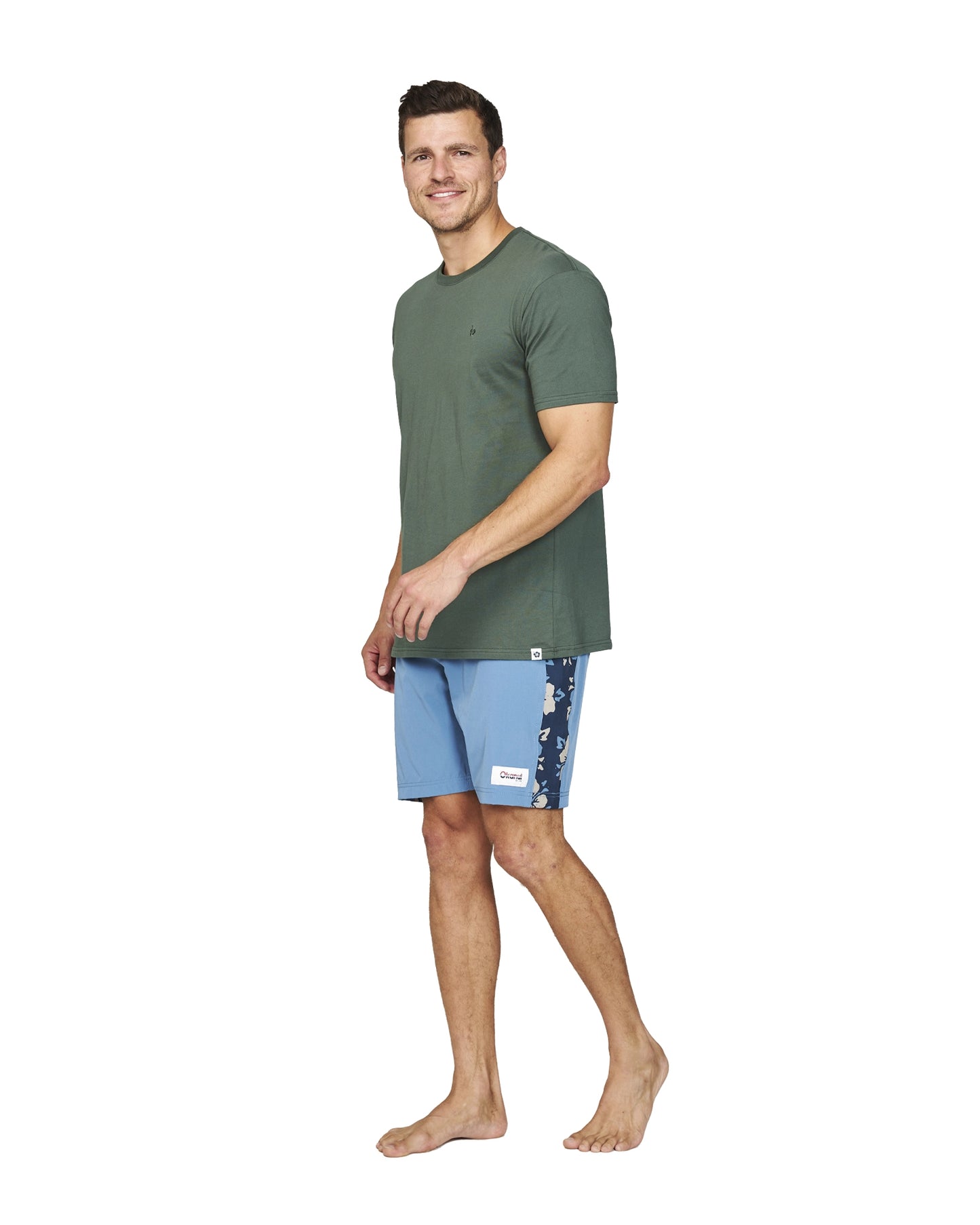 A male model wearing the Okanui Collage Boardrider Boardshort in Steel colour and a green t-shirt.