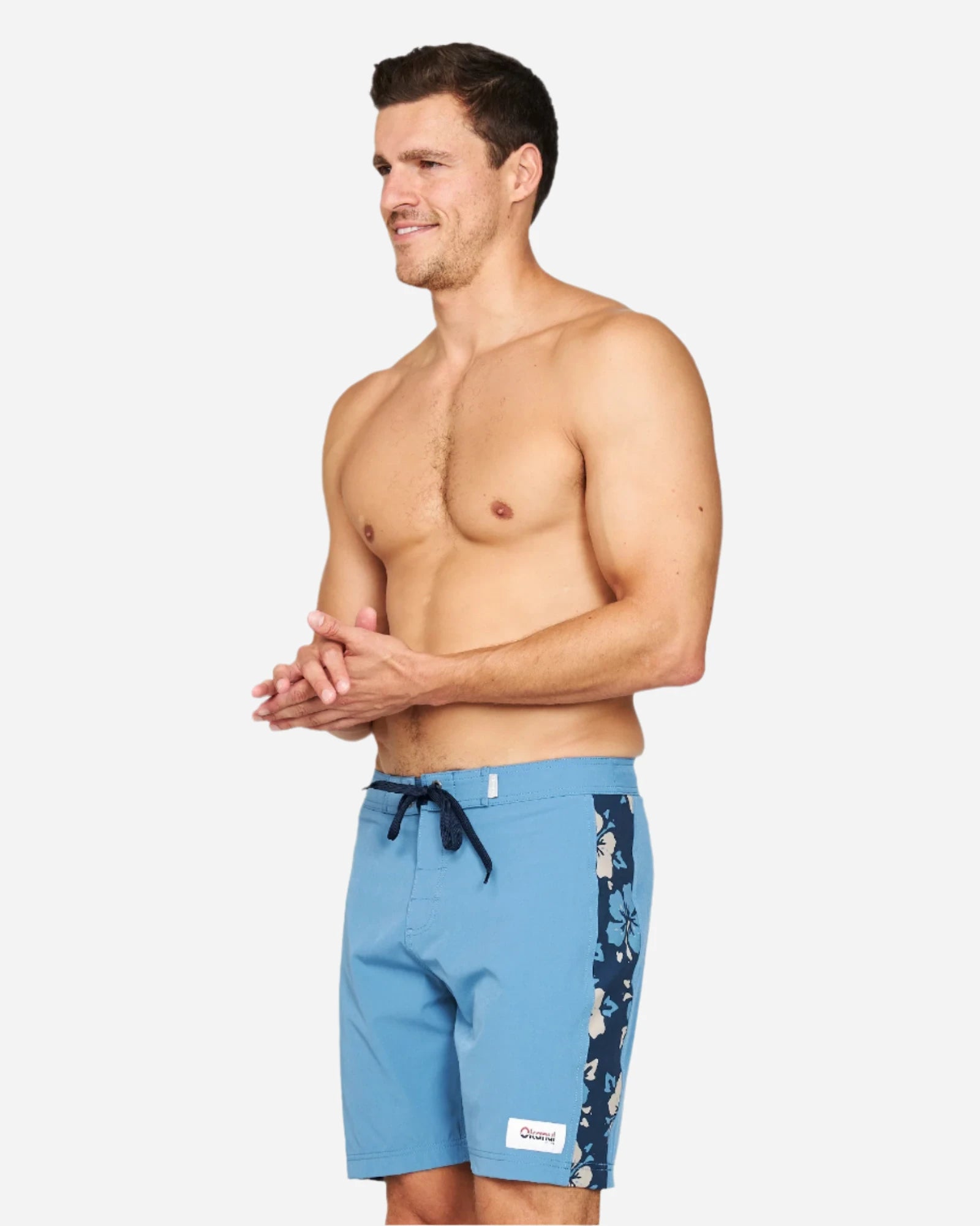 A side view of a male model wearing the Okanui Collage Boardrider Boardshort in Steel colour.