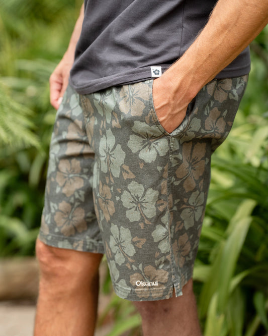 Close up view of the Okanui Stonewall Heritage Walk Short in Forest colour worn by a male model posing outside with his hand in the pocket.