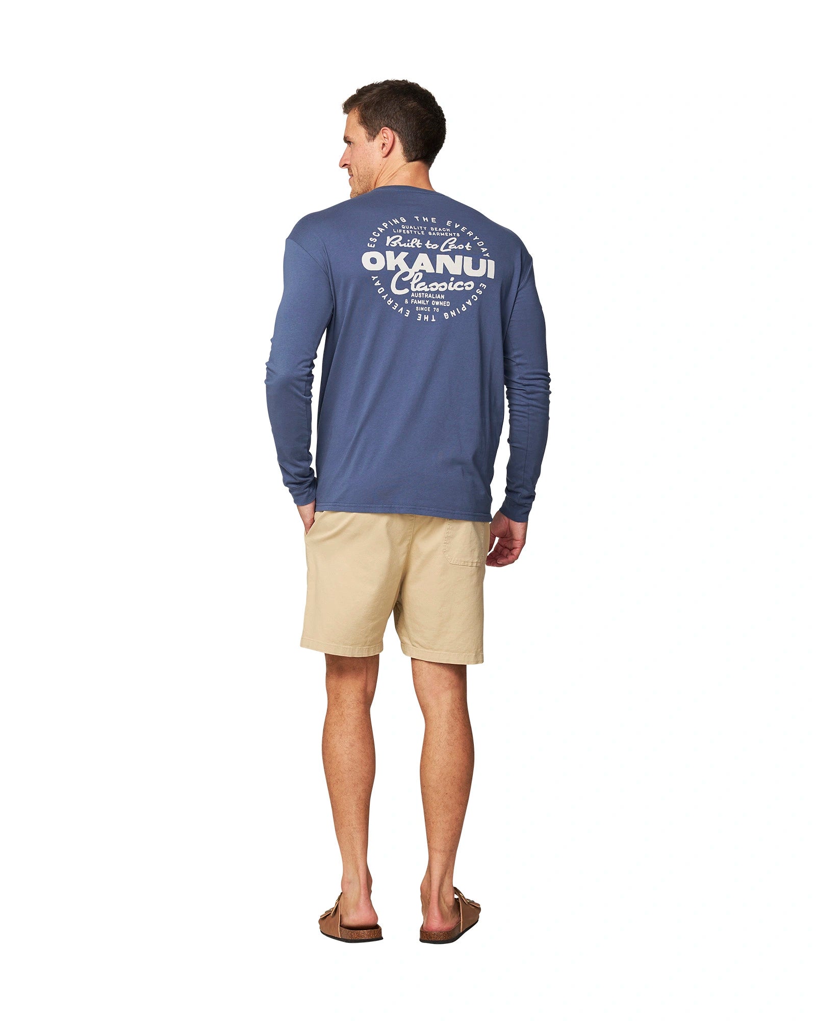 Hand in pocket pose of a male model wearing the Okanui Last Stand long sleeve t-shirt in Washed Navy color