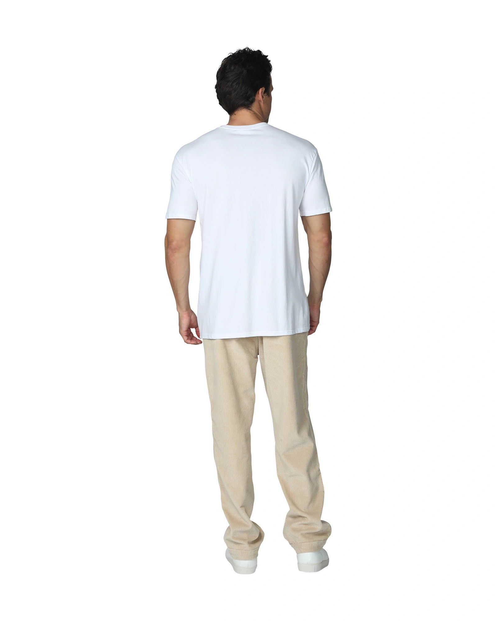 A full back view of a male model wearing a plain white t-shirt and the Okanui Bay Corduroy Pant in Oat colour.