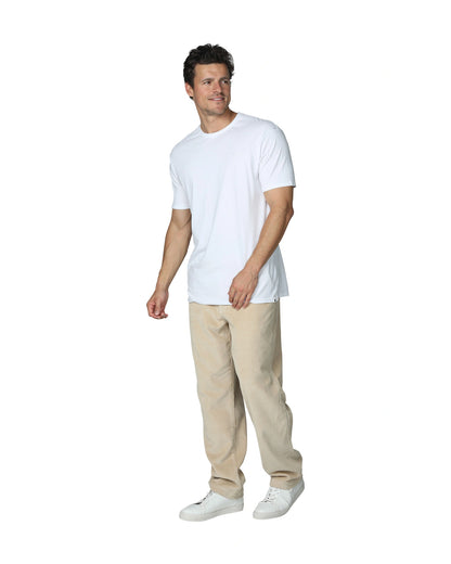 A casual pose of a male model wearing a white t-shirt and the Okanui Bay Corduroy Pant in Oat colour paired with white shoes.