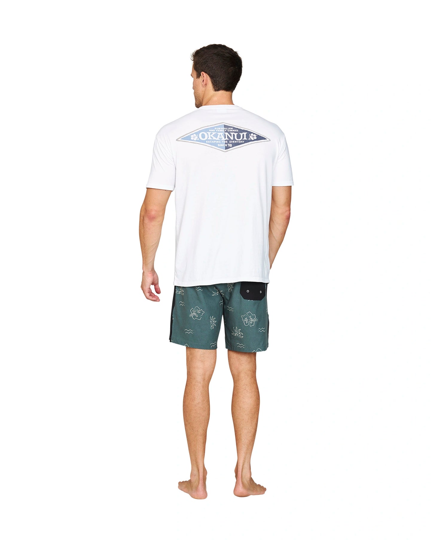 Back view of a male model wearing a white t-shirt and the Okanui Rising Sun Stretch Swim Shorts in Forest colour.