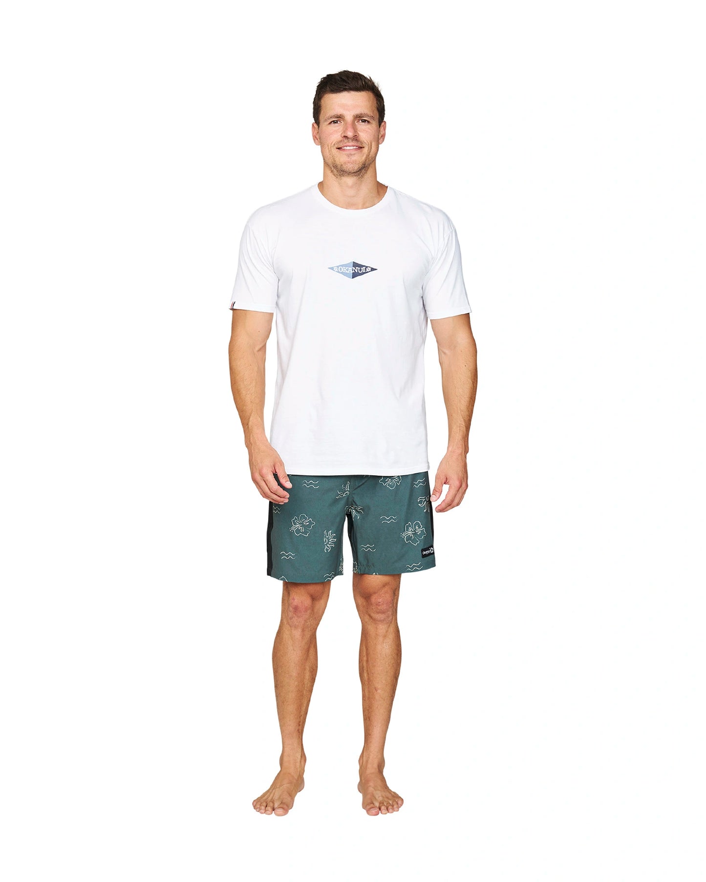 A male model wearing a white t-shirt and the Okanui Rising Sun Stretch Swim Shorts in Forest colour.