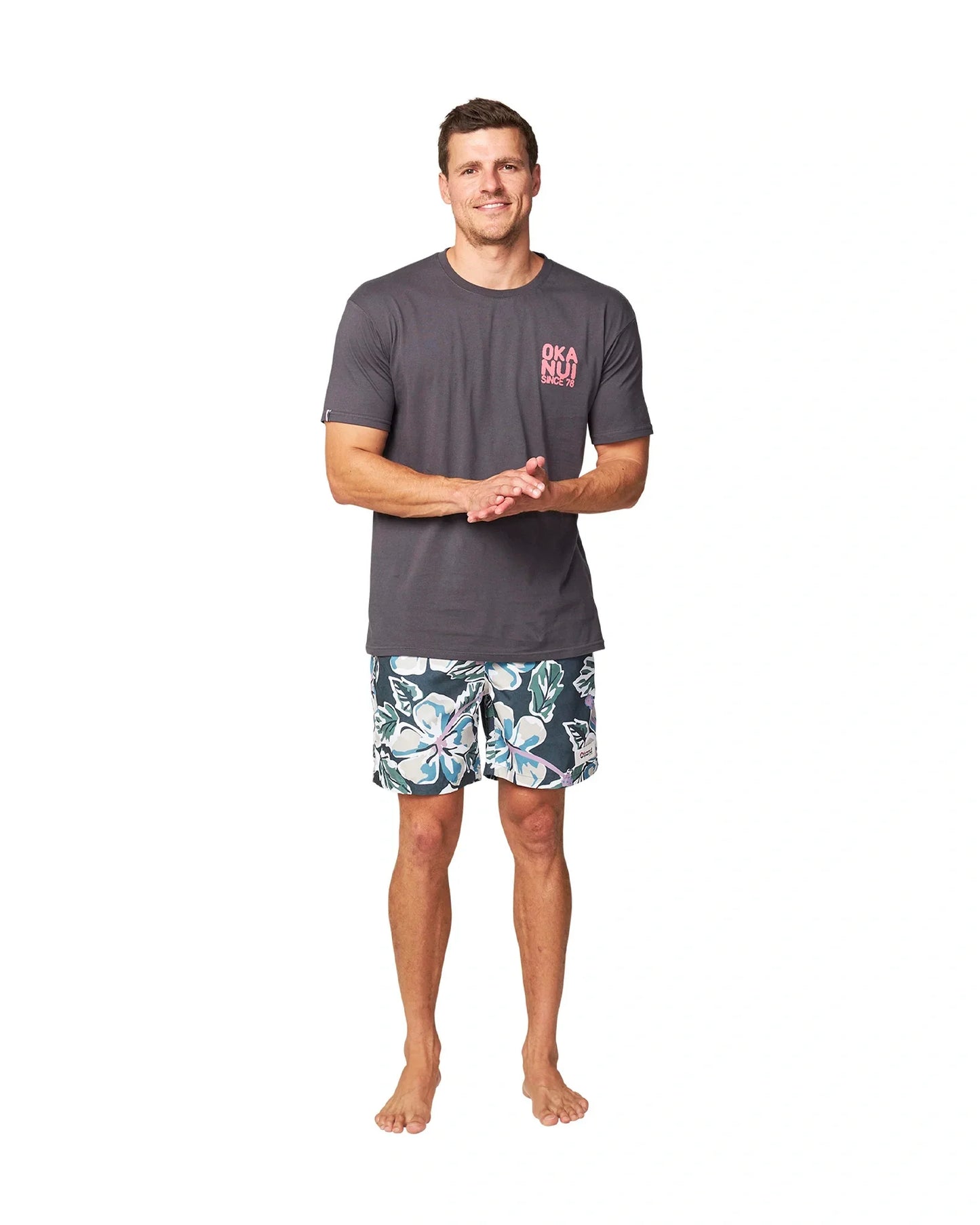A male model wearing a dark grey t-shirt and the Okanui Flora Fatigue Swim Shorts.