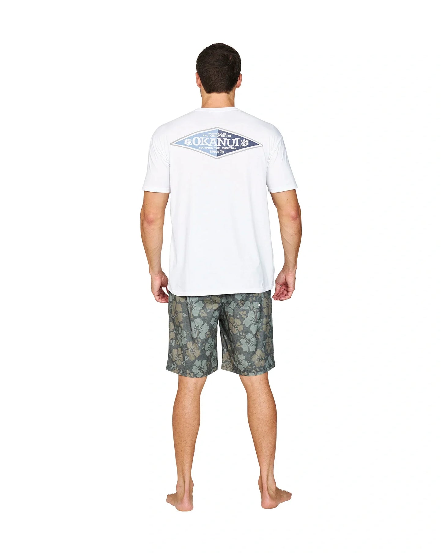 Back view of a male model wearing the Okanui Cornerstone T-shirt in white colour featuring a back print.