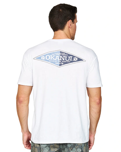 Closer back view of a male model wearing the Okanui Cornerstone T-shirt in white colour featuring a back print with "Okanui" on a rhombus multicolor shape.