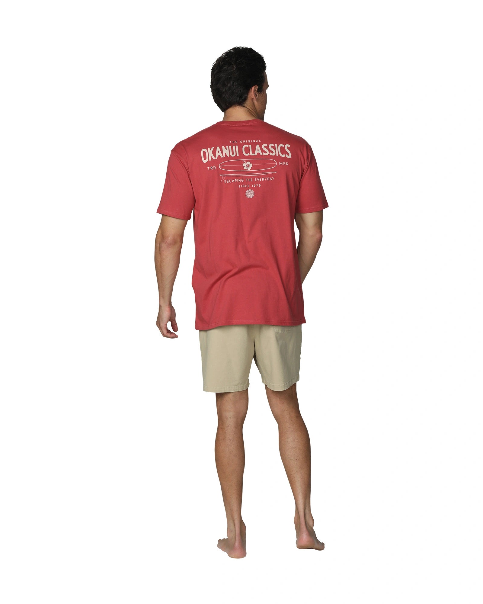 A full back view of a male model wearing Okanui's Boardriders Men's T-Shirt in Rust colour showcasing the back print with the words "Okanui Classics".