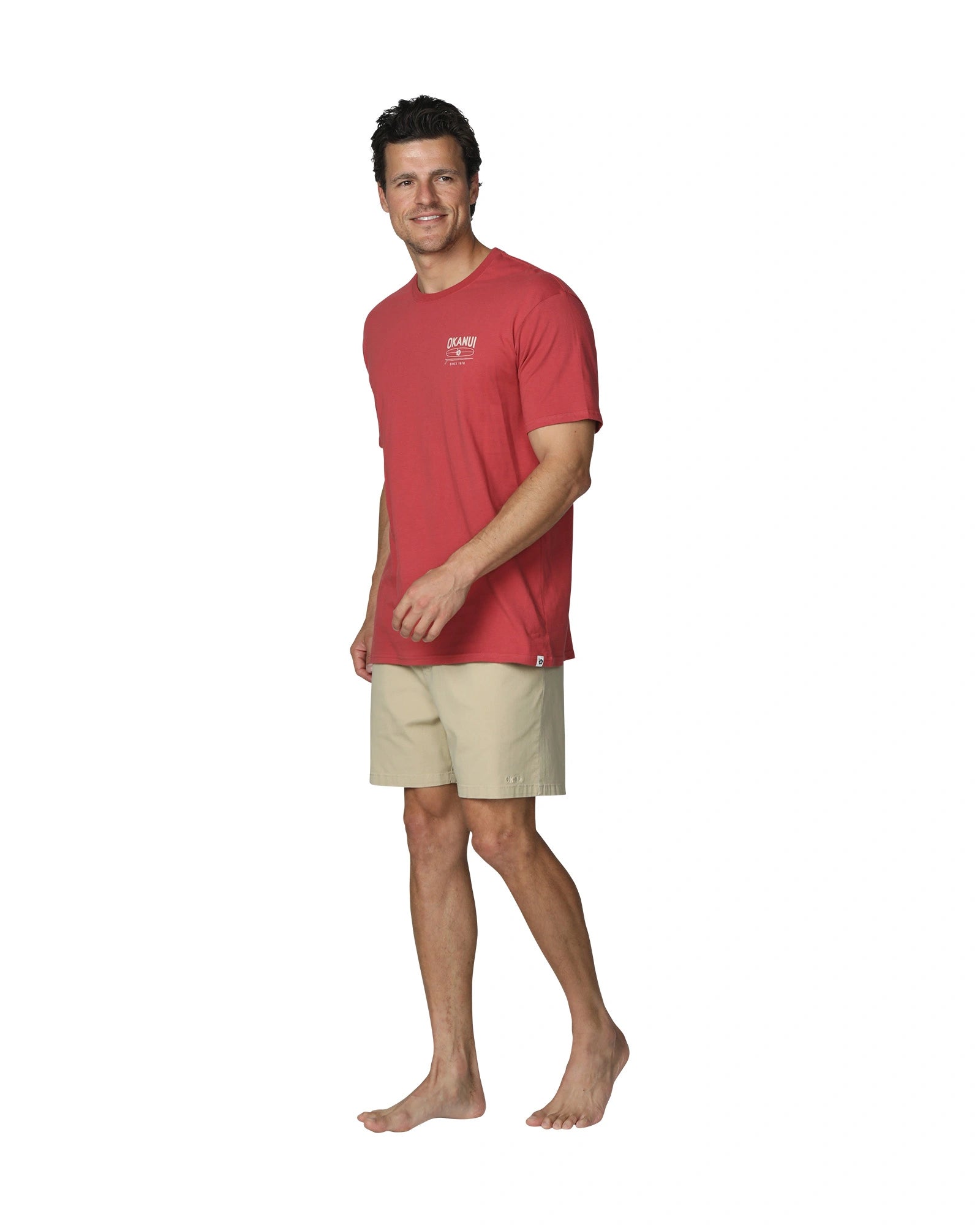 A full body slightly side view of a male model wearing Okanui's Boardriders Men's T-Shirt in Rust colour.