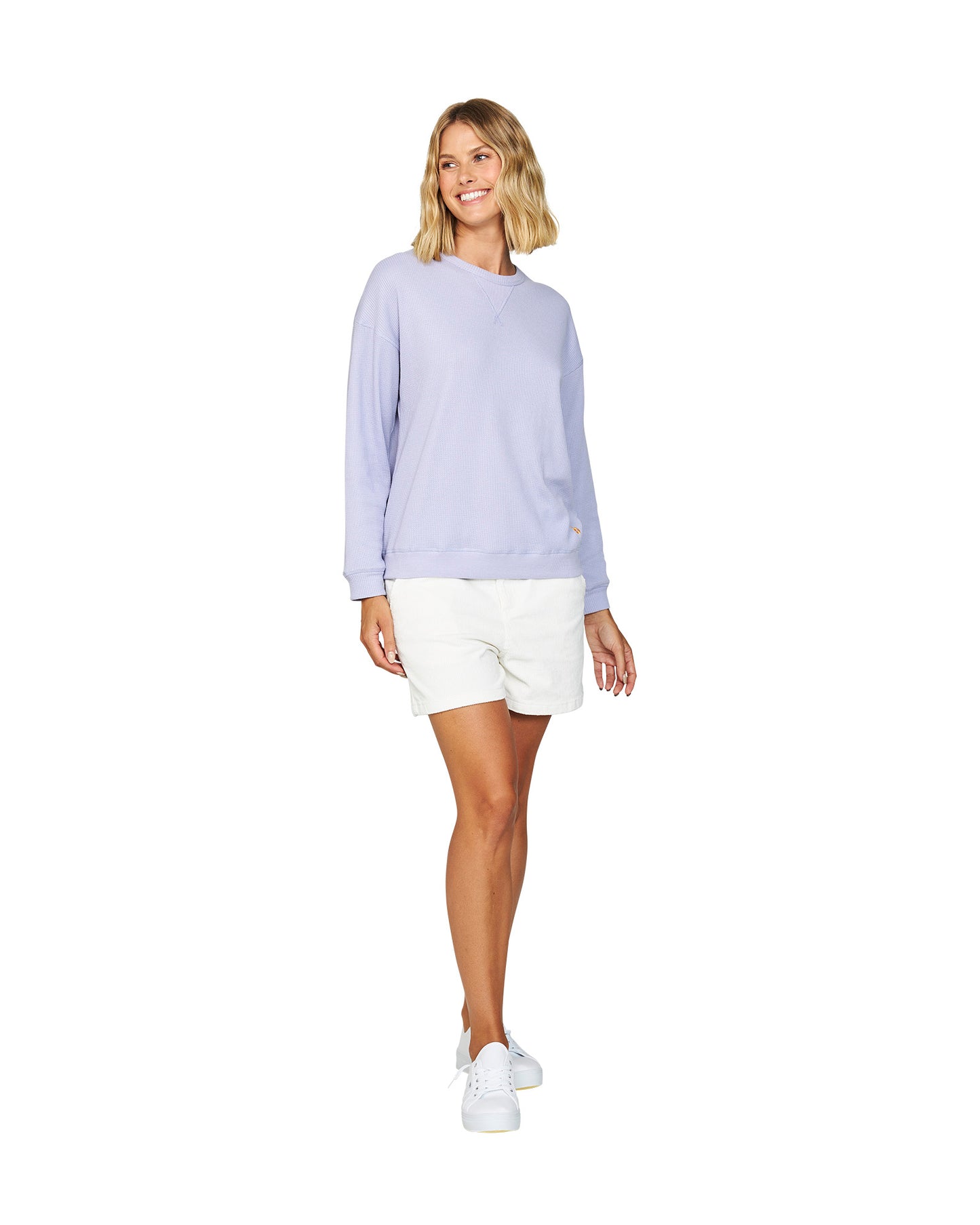 Full body front view of a female model wearing the Okanui long sleeve waffle knit jumper in Gelato Lilac variant