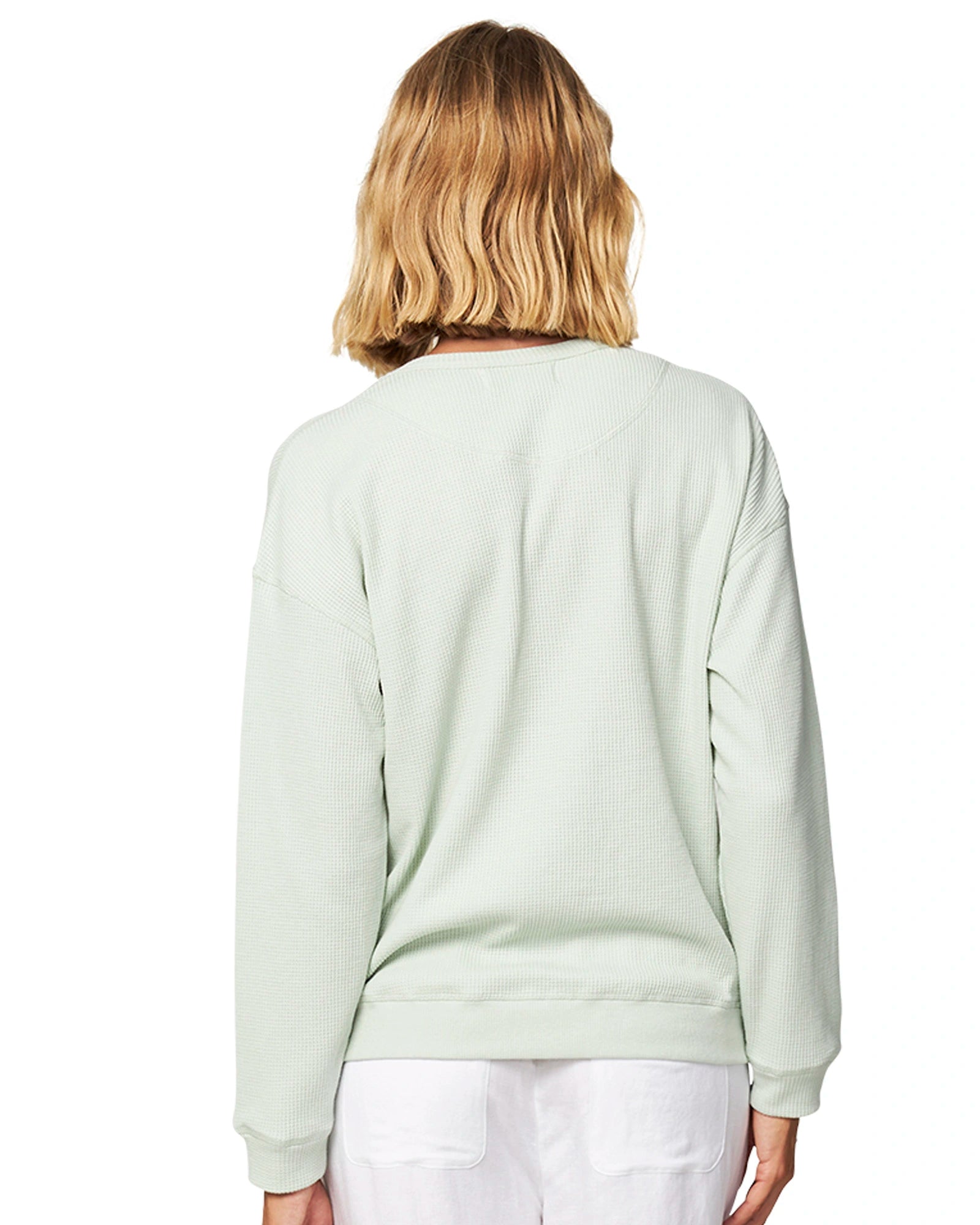 Close up back view of a blonde female model wearing the Okanui long sleeve waffle knit jumper in gelato sage color