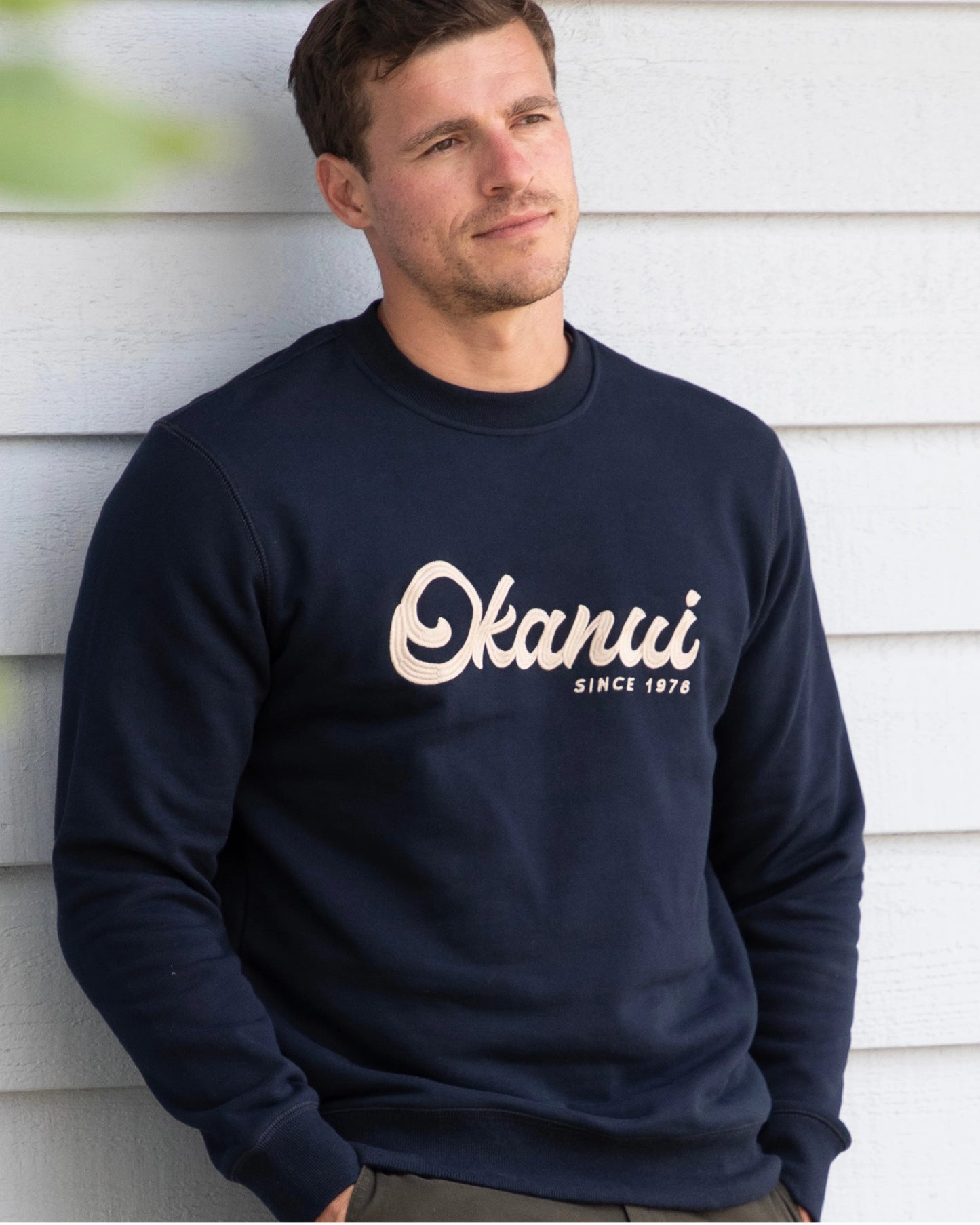 A navy blue-colored sweatshirt with Okanui logo in the center. 