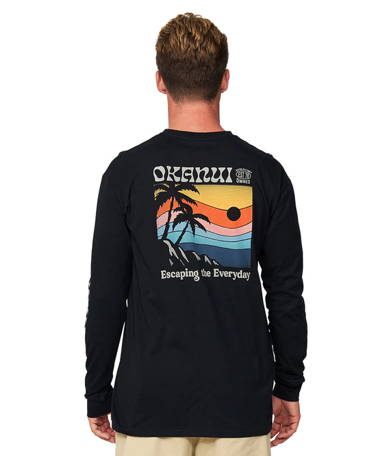 The back view of the model wearing the Okanui Splendor Long Sleeve T-shirt featuring a print of animated beach on the back.