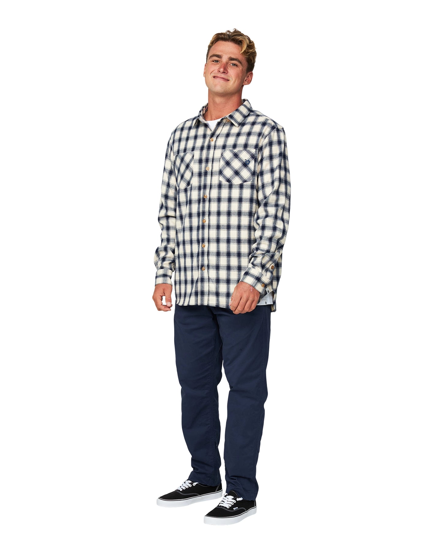 A male model wearing navy pants and the Okanui Long Sleeve Flannel Hiker Shirt featuring its compatibility.