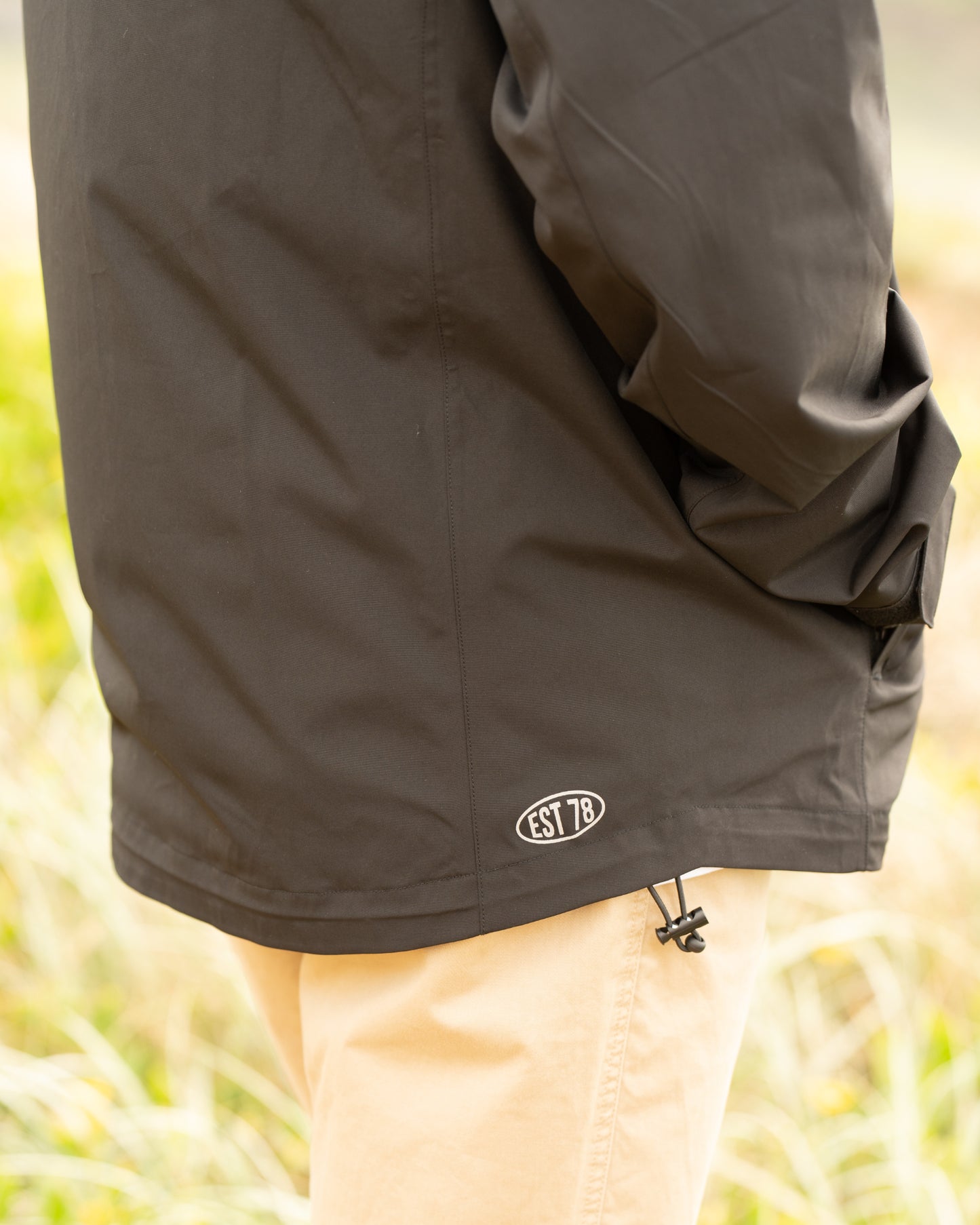 Mens surf jacket in black color with EST 78 logo on the lower back side. 