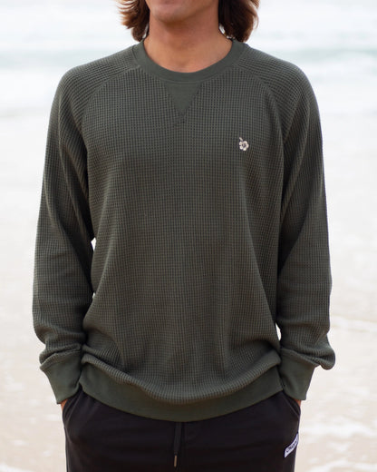 A close view of a model posing outdoor wearing the Okanui Waffle Jumper Crew in Forrest Green colour.