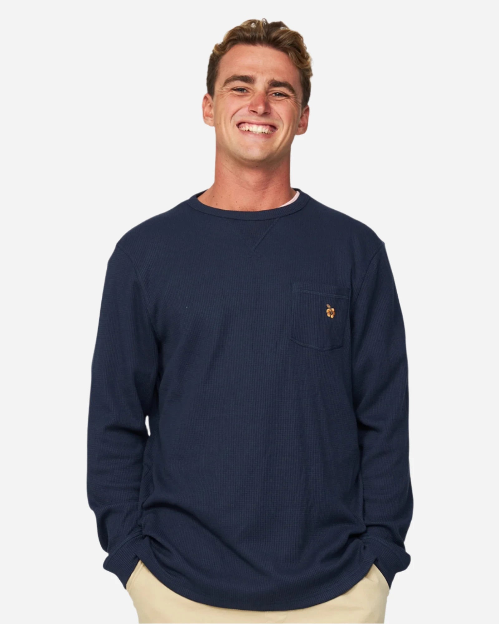 A smiling model wearing the Okanui Long Sleeve Waffle Tee over a t-shirt.