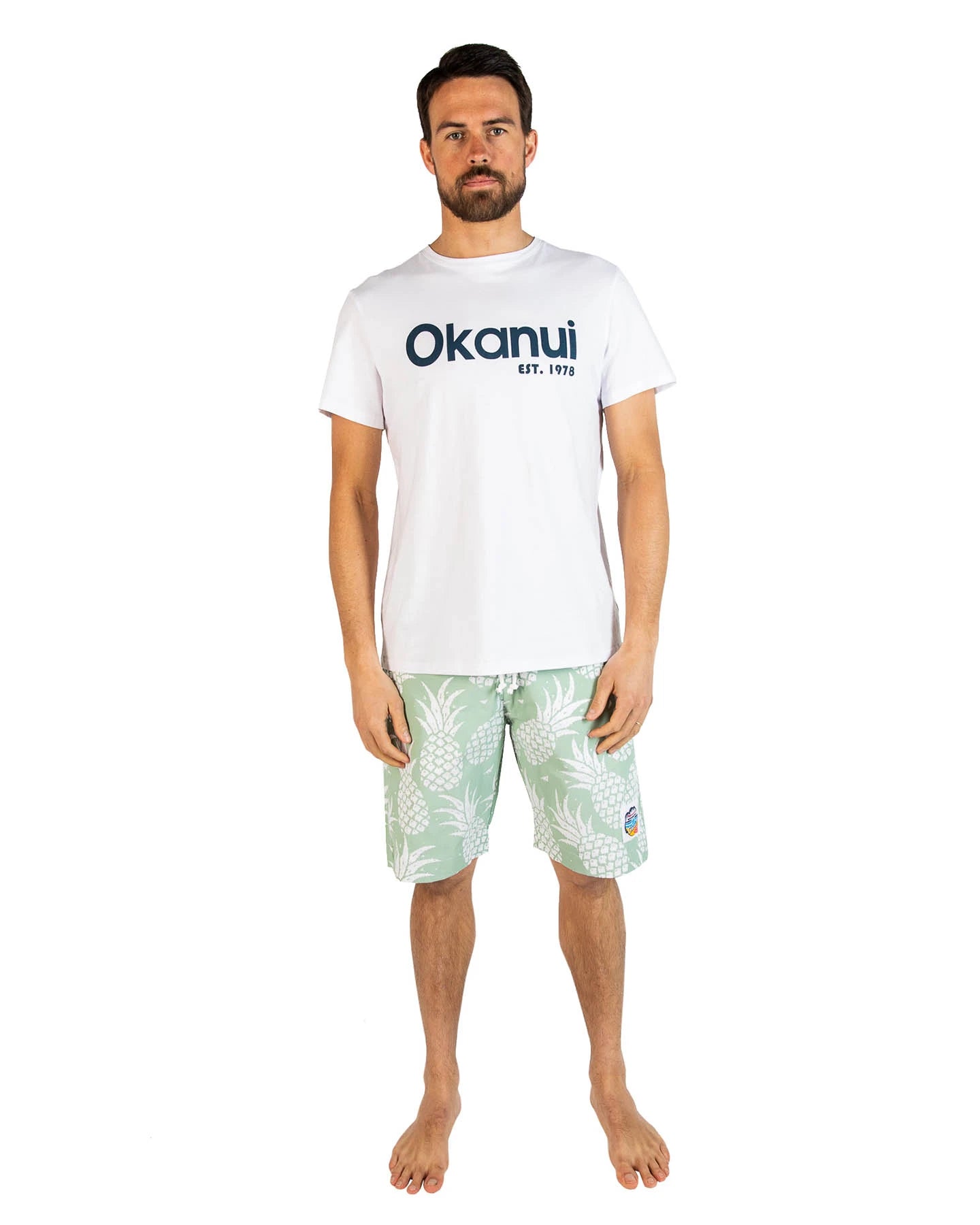 A male model wearing the Okanui Logo Tee in white colour and the Okanui Pineapple Classic Shorts.