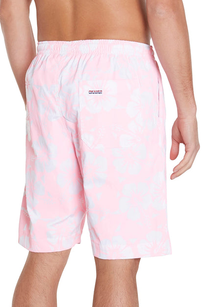 A person wearing light pink floral swim trunks is shown from the back. The swim trunks have a pocket on the back with a small visible label above it.