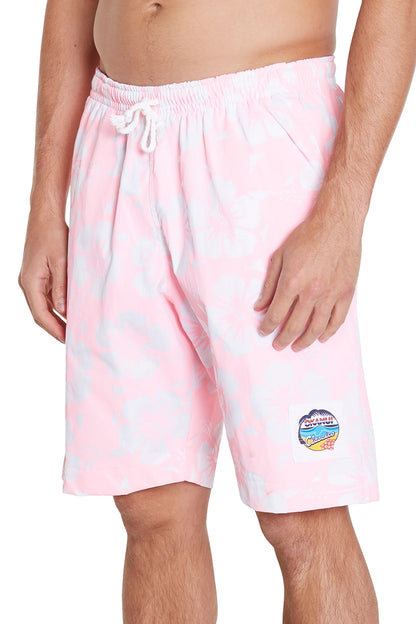 A man wearing light pink swim shorts with a white subtle pattern and a small colorful patch. The shorts have a white drawstring at the waist.