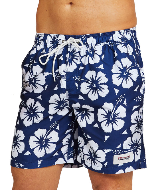 A half-body view of the Okanui Swim Trunks in navy color featuring a Hibiscus flower prints all over the shorts worn by a male model.