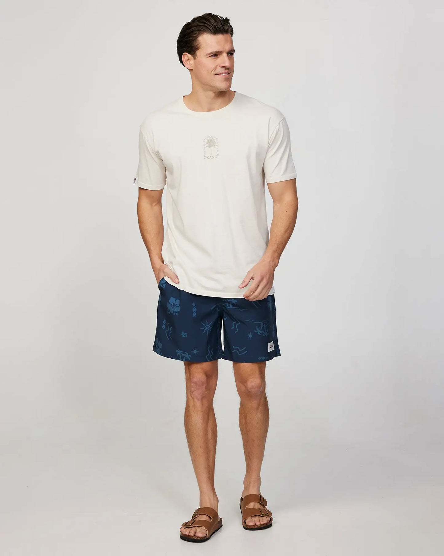 Full body front view of a male model wearing the Okanui Mens Seascape Stretch Swim Short in Navy Natural